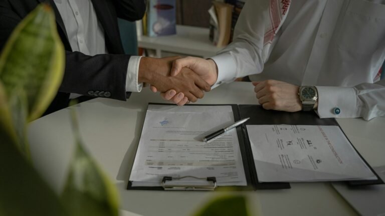 Aperto de mãos sobre contrato assinado em mesa de reunião