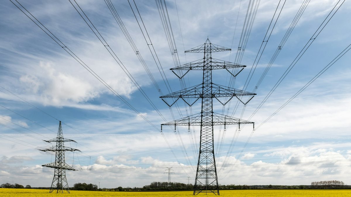 Torres e linhas de transmissão de energia sobre campo amarelo